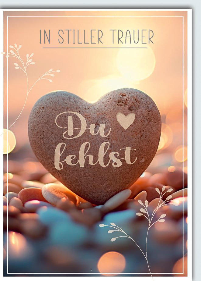Trauerkarte Einfühlsam: Steinherz in warmen Händen mit "Du fehlst", sanfte Lichter